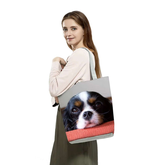 Woman carrying a Cavalier King Charles Spaniel tote bag featuring a cute dog face design.